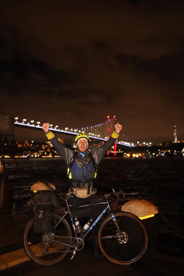 Damian Stawicki z rowerem w Stambule podczas wyprawy #KilometryDlaKazia – most Bosforski w tle