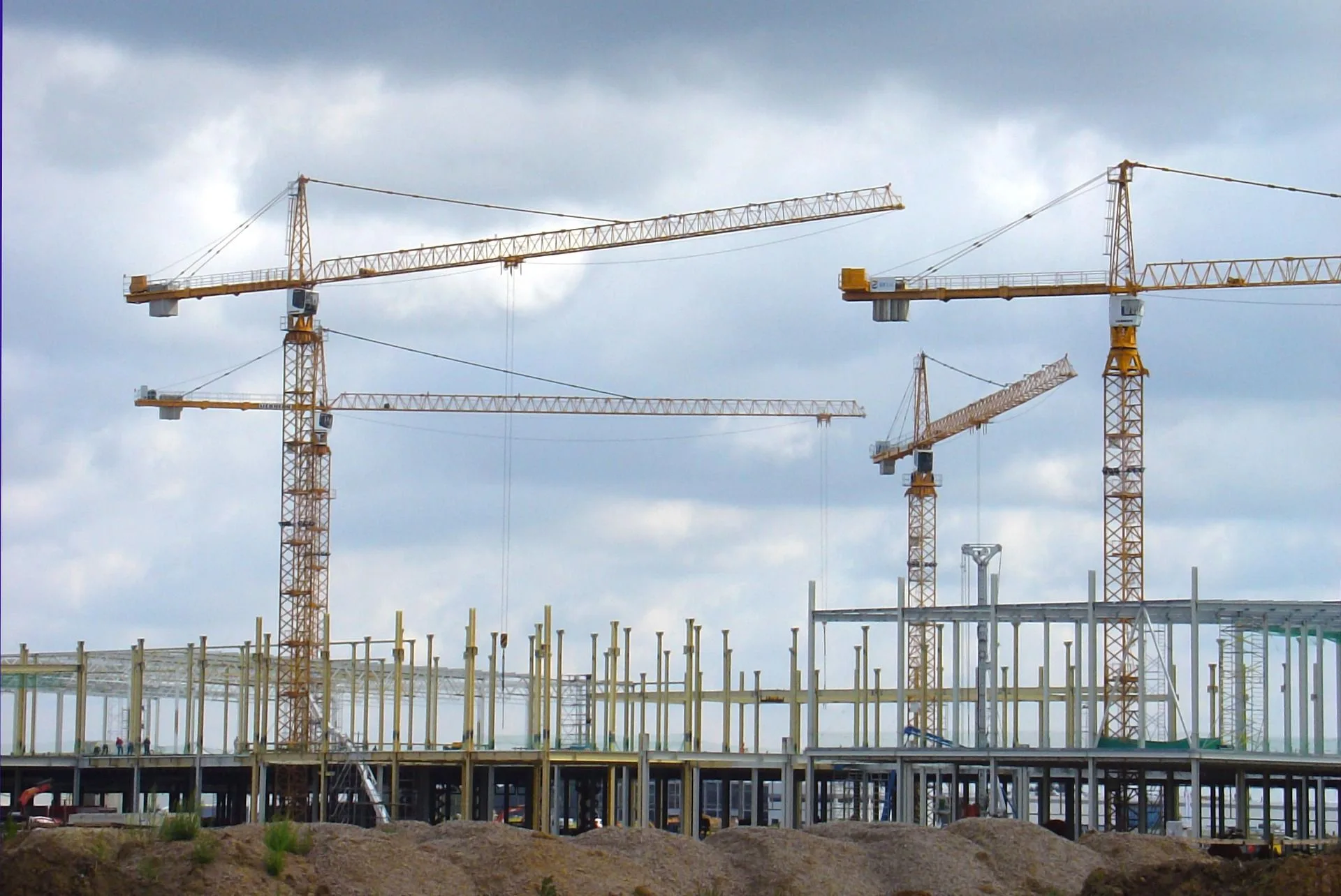 Budowa hali przemysłowej – konstrukcja obiektu w trakcie realizacji z użyciem żurawi wieżowych