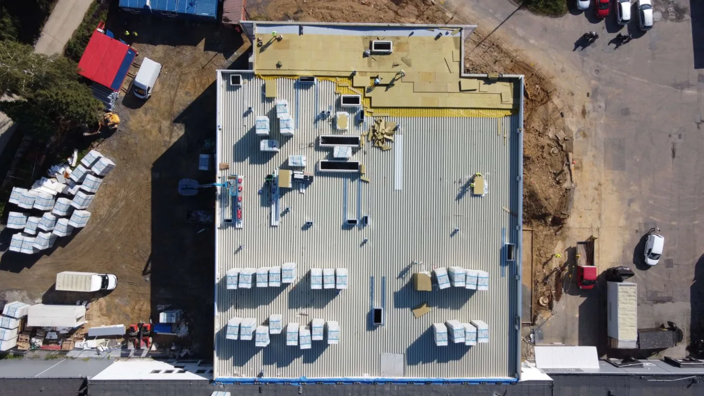 Widok z góry na dach budynku Karmello – prace instalacyjne i przygotowanie warstw dachu w trakcie realizacji przez VSYSTEM