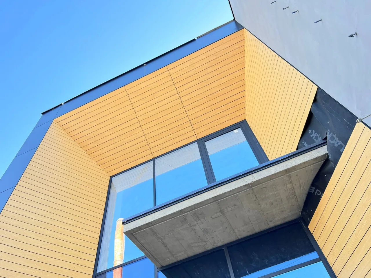 Detal elewacji budynku Karmello Chocolatier – wykończenie fasady z dużymi przeszkleniami i okładziną zewnętrzną