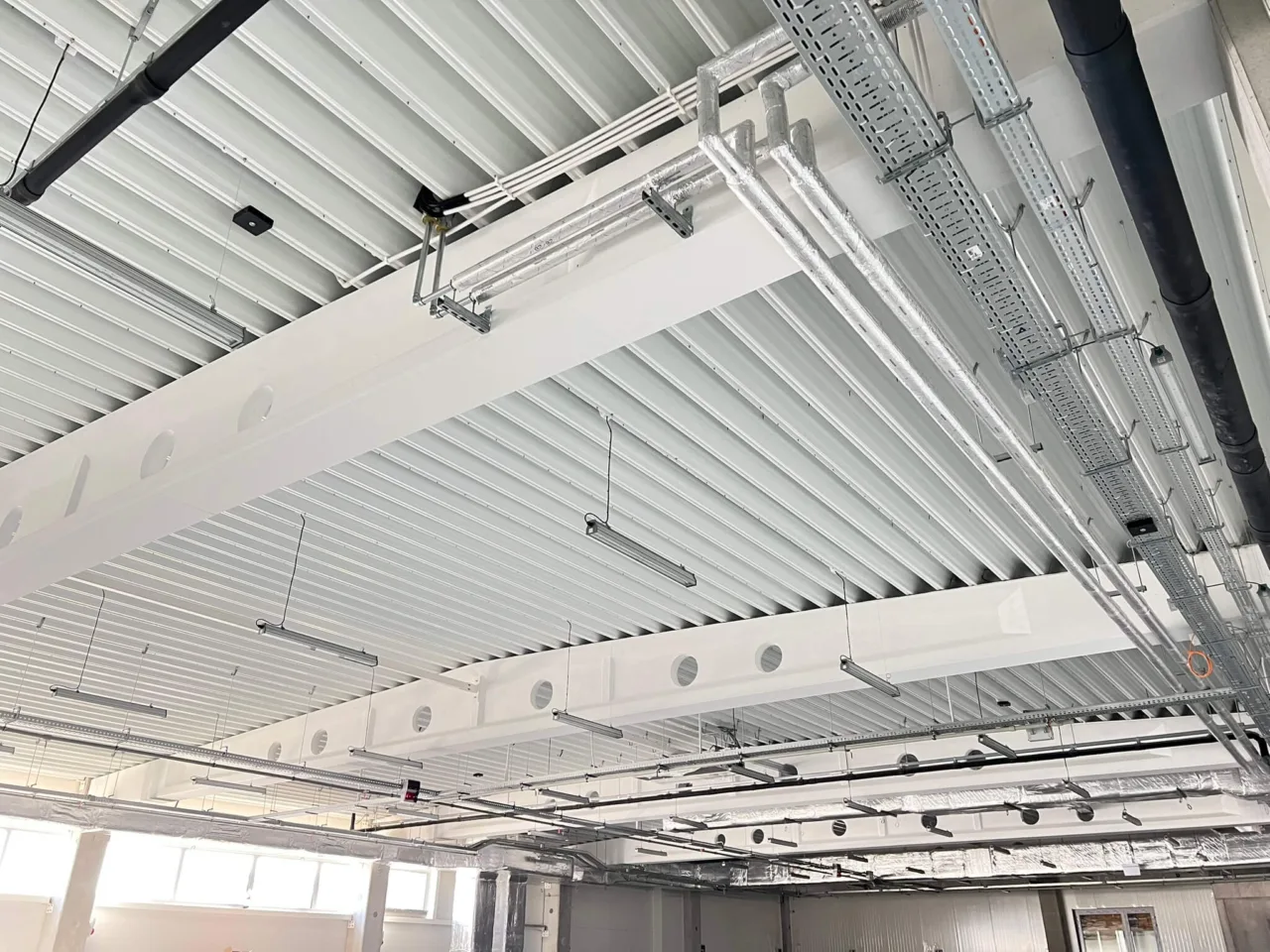 Wnętrze hali produkcyjnej Karmello – widoczne instalacje pod stropem oraz przygotowanie przestrzeni technicznej