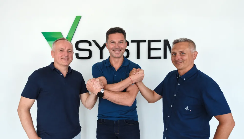Piotr Krzyżowski z Tomaszem Kowalskim i Wojciechem Czarnynogą na tle logo VSYSTEM.